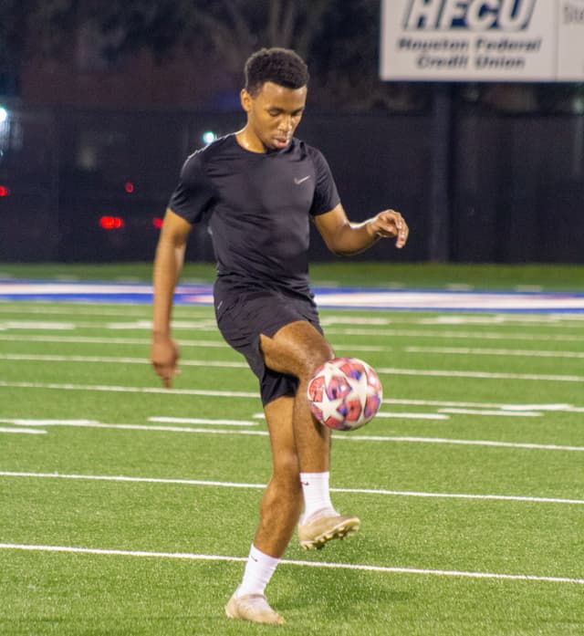 Chiedozie Ehileme is juggling a football on a field